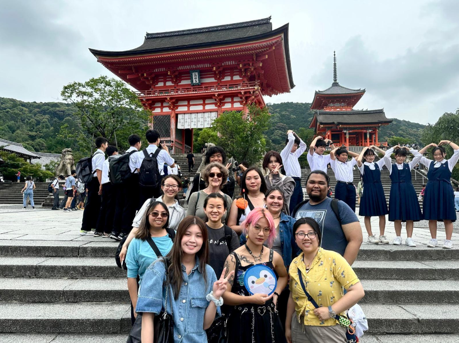 Faculty Led Program - Japan A diverse group of people poses for a picture in front of a beautifully detailed temple structure.